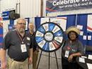 ARRL Emergency Communications and Field Services Director Josh Johnston, KE5MHV; Hudson Division Vice Director David Galletly, KM2O, and Puerto Rico Section Manager Carmen Greene, KP4QVQ, with the “prize wheel” at the ARRL Year of the Club booth.
